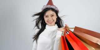 一个快乐的年轻女人，戴着帽子，拿着一个白色背景的购物袋