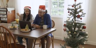 年轻的亚洲夫妇通过在线视频通话庆祝圣诞节。在冠状病毒隔离期间保持社交距离和自我隔离