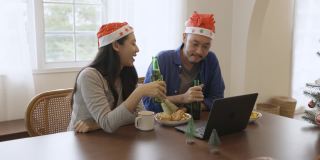 年轻的亚洲夫妇通过在线视频通话庆祝圣诞节。在冠状病毒隔离期间保持社交距离和自我隔离