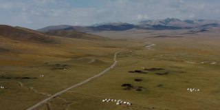 俯瞰风景优美的荒野蒙古包营地和吉尔吉斯斯坦松吉湖的公路