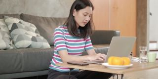 亚洲自由职业女性，在家用手机和笔记本电脑工作。