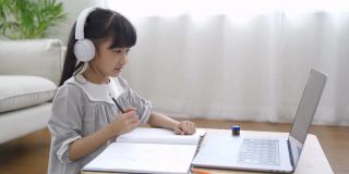 亚洲女孩用笔记本电脑做作业。