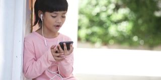 漂亮的亚洲女孩戴着耳机，用手机听音乐