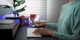 亚洲妇女用电脑装饰她的客厅为圣诞节。