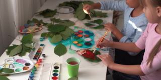 给孩子们的秋季工艺品。用枫叶做成的动物狐狸。儿童艺术和创造力。天然材料制成的工艺品。女孩用颜料画画。
