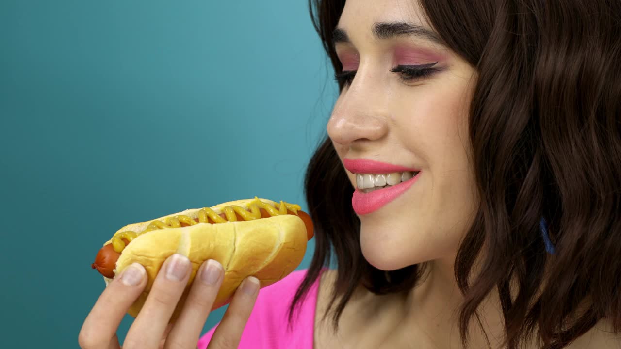 一个女人在吃蘸酱的热狗。