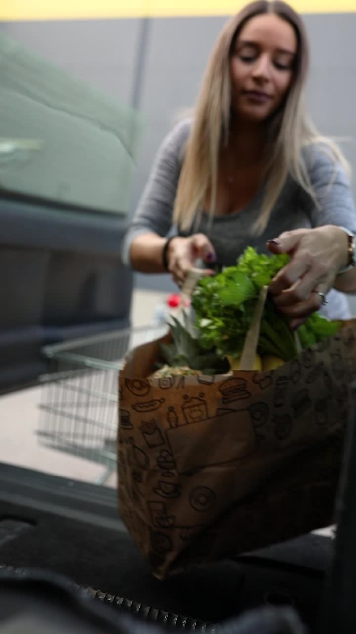 一个孕妇正在把食品杂货装进汽车后备箱