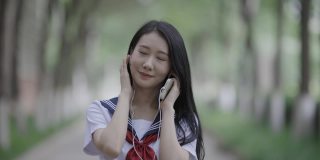 年轻的亚洲女性，戴着耳机，走在校园里
