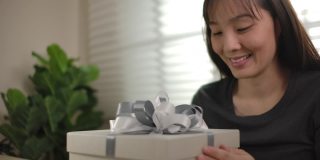 快乐的亚洲女人打开礼品盒