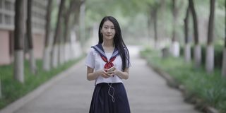 年轻的亚洲女性，戴着耳机，走在校园里