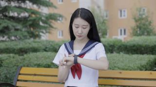 年轻的亚洲女性戴着口罩坐在长凳上看着智能手表视频素材模板下载