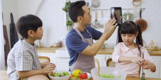 亚洲的父亲和孩子们在电子平板电脑上与妈妈进行视频通话。