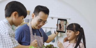 亚洲的父亲和孩子们在电子平板电脑上与妈妈进行视频通话。