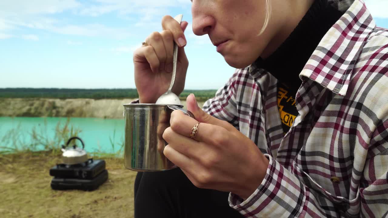 一个满头白发的女人，特写镜头，拿着勺子用金属杯子吃饭。