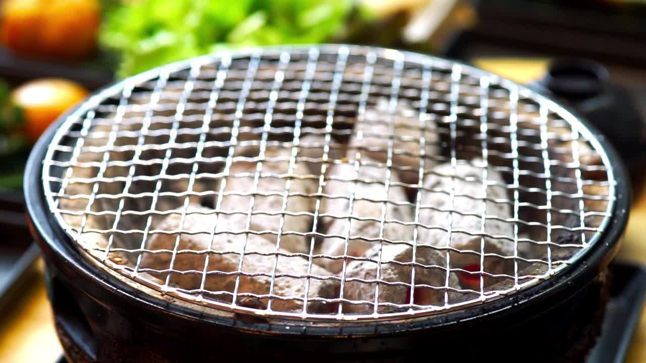 日本餐厅的炉子上放着用筷子夹着和牛烤肉的手。