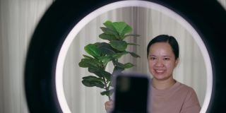 亚洲女性在家卖植物，用智能手机直播的特写镜头