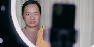 亚洲女性用智能手机在线直播在家卖包包
