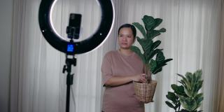 亚洲女性用智能手机在线直播，在家里卖人造植物
