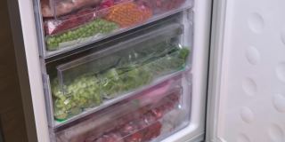 冷冻青豆。冷冻食品存储。生食饮食装有切片蔬菜和水果的塑料盒和袋子