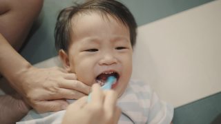 父母正在用牙刷帮儿子刷牙。视频素材模板下载