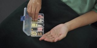 亚洲妇女从药片容器中取出药片