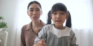 一位亚洲母亲在网上视频课上给女儿讲解家庭作业