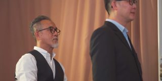 亚洲华人高级男裁缝用卷尺测量他的客户的身体尺寸为新的运动夹克在工作室制作，并写下数字平板电脑记录数字