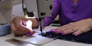 一名女裁缝在缝纫机上缝纫的4K高清视频，针和线的运动。