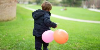 快乐的小男孩拿着气球跑在外面