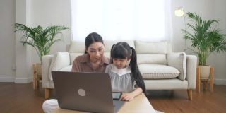 亚洲母亲和女儿与妈妈一起用笔记本电脑做作业