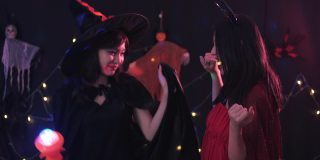 两个亚洲妇女在万圣节服装跳舞和在家庭聚会的乐趣