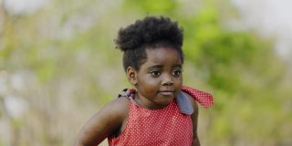 非裔美国女孩穿着红色圆点衬衫快乐地站在花园里夏天。学龄前儿童快乐成长。周末活动快乐家庭生活理念。概念儿童节