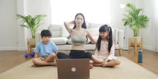 亚洲母亲和孩子在COVID-19大流行期间在家锻炼。