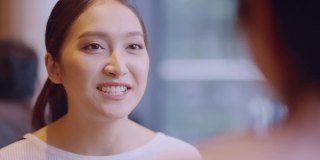 年轻迷人的亚洲女性微笑积极的交谈与朋友在咖啡馆，沟通和友谊的概念-微笑的年轻女性与咖啡杯在咖啡馆