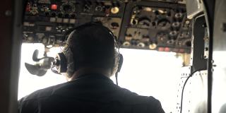男性飞行员在飞行过程中工作和坐在飞机驾驶舱的后视图。Avki