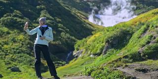 徒步旅行和生态旅游女士拍摄博客在山谷的间歇泉Avki