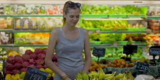 一名年轻女子在超市水果部挑选一串香蕉