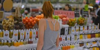 妇女在超市选购健康食品，饮料，果汁和水果