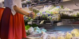 女士在超市挑选包装好的新鲜蔬菜。概念购物，塑料，有机