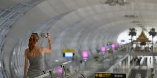 一名女子在国际机场大厅门口用智能手机背面拍照