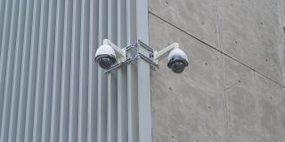 城市建筑墙上的双面闭路电视摄像头。在灰色的墙上安装了现代化的监控摄像头