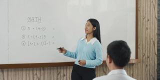 年轻的亚洲教师在教室里教学生。