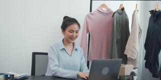 一位亚洲企业家正在准备可以装在纸盒里卖给顾客的衣服。