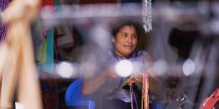 快乐的拉丁女人在工作。一个墨西哥女人微笑着在一家典型的服装店工作