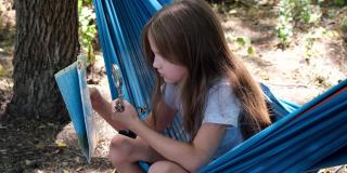 小女孩坐在吊床上看着夏令营里的地图。童军正在森林里进行定向运动。儿童概念地图阅读技巧