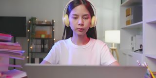 开朗美丽的亚洲女人在白色t恤和看笔记本电脑在视频电话会议和聊天的朋友在网上。