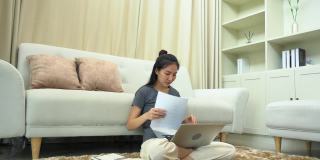 一名亚洲妇女在膝上放着笔记本电脑完成工作后将文件扔进客厅。