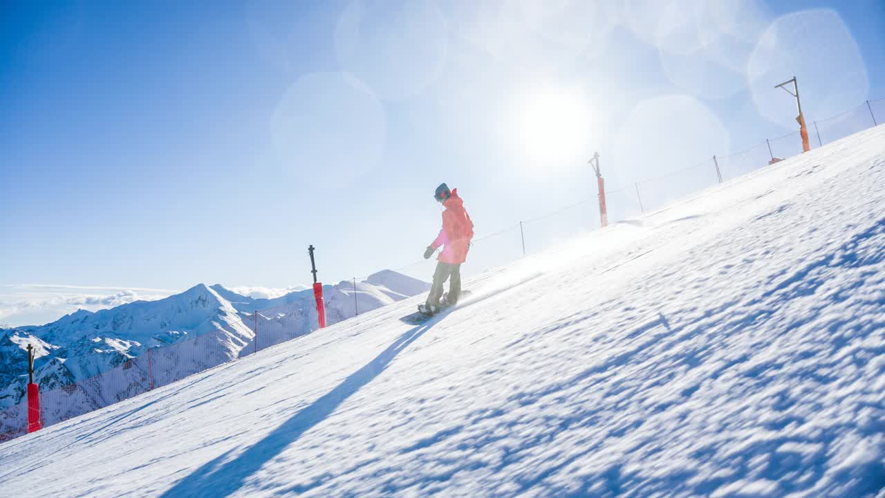 滑雪板运动员在滑雪道上滑行，在转弯时喷着雪，背景是山脉