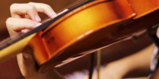 一个年轻的小提琴手模糊的左手按下小提琴颈上的弦，水平
