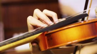 一个年轻的小提琴手模糊的左手按下小提琴颈上的弦，水平视频素材模板下载